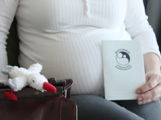 Schwangere Frau mit Babybauch und Mutterpass